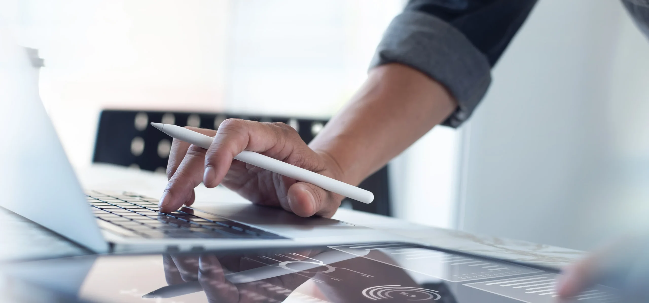 Person using a laptop with stylus pen, working on digital design or technology project.