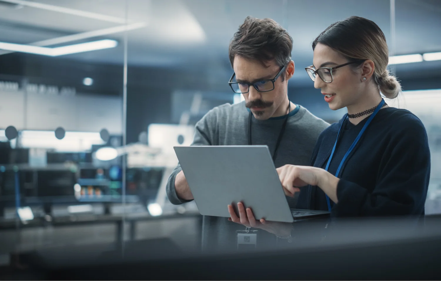 Two professionals collaborating on a laptop in a modern office setting.