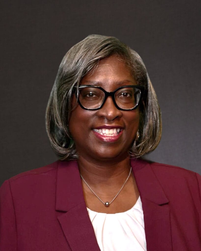 Terri Mosley professional headshot wearing dark glasses, and a dark red jack with a dark background