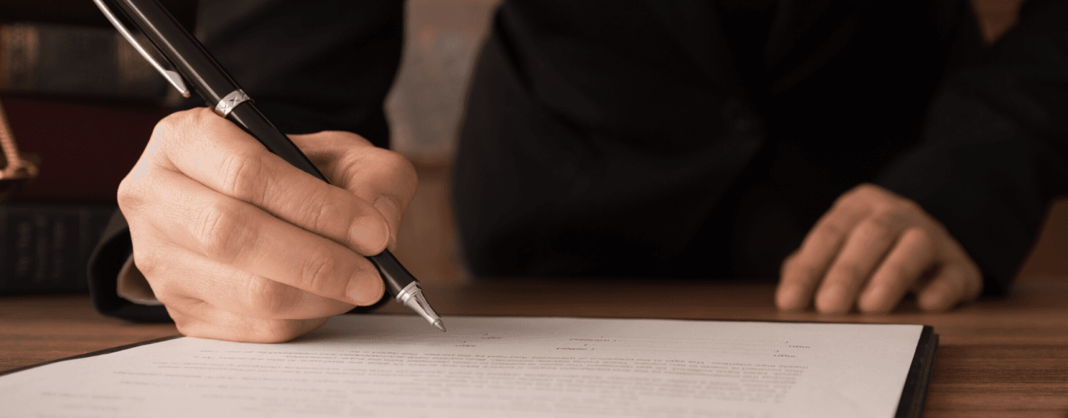Business professional signing a legal document with a pen, emphasizing contract agreement and formal procedures.